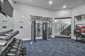a gym with weights and cardio equipment in the corner of a room